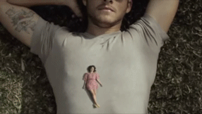 GIF of a woman four inches tall laying on the chest of a man with his hands behind his head. He moves his hand to cover her like a blanket.