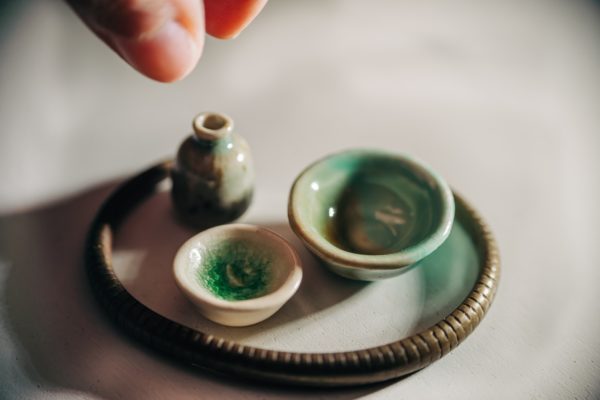 person holding 2 tiny green and white ceramic bowls