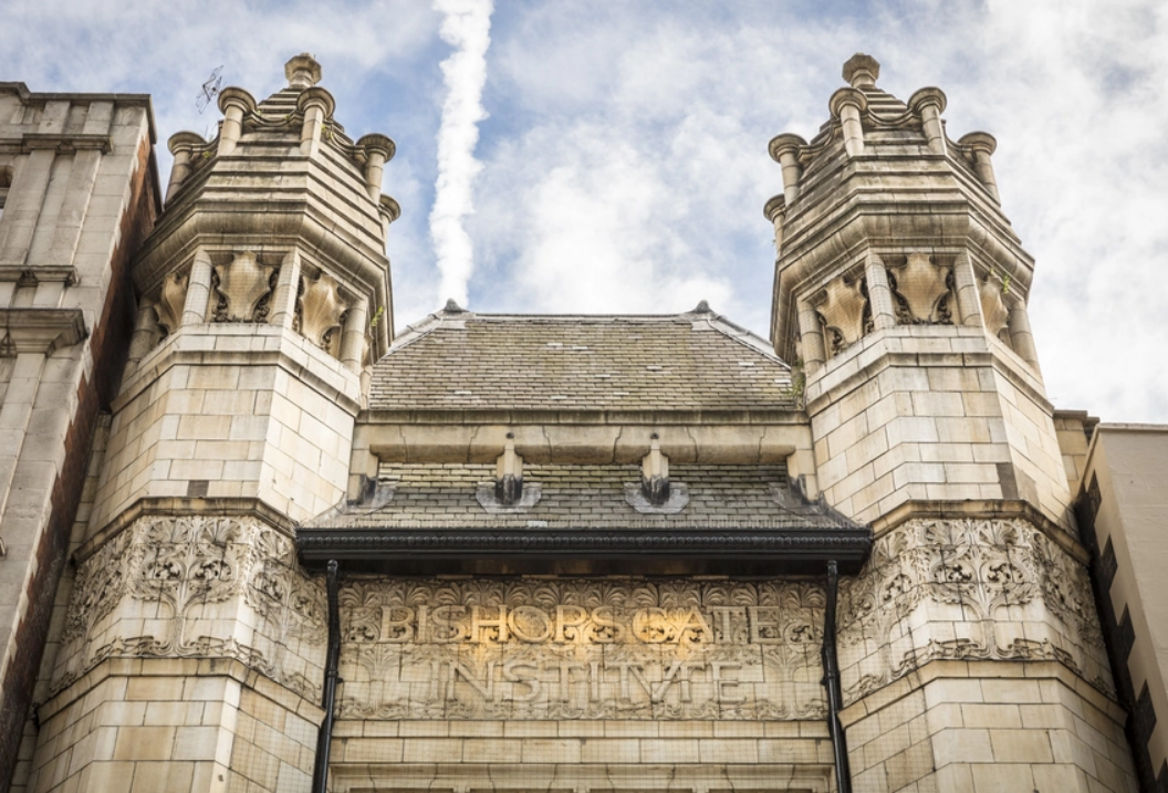 Photo of the imposing entrance of the Bishopsgate Institute in London, a stone building fromt eh Victorian era with two towers and many flourishes carved into an elaborate design. Image from the BG website.